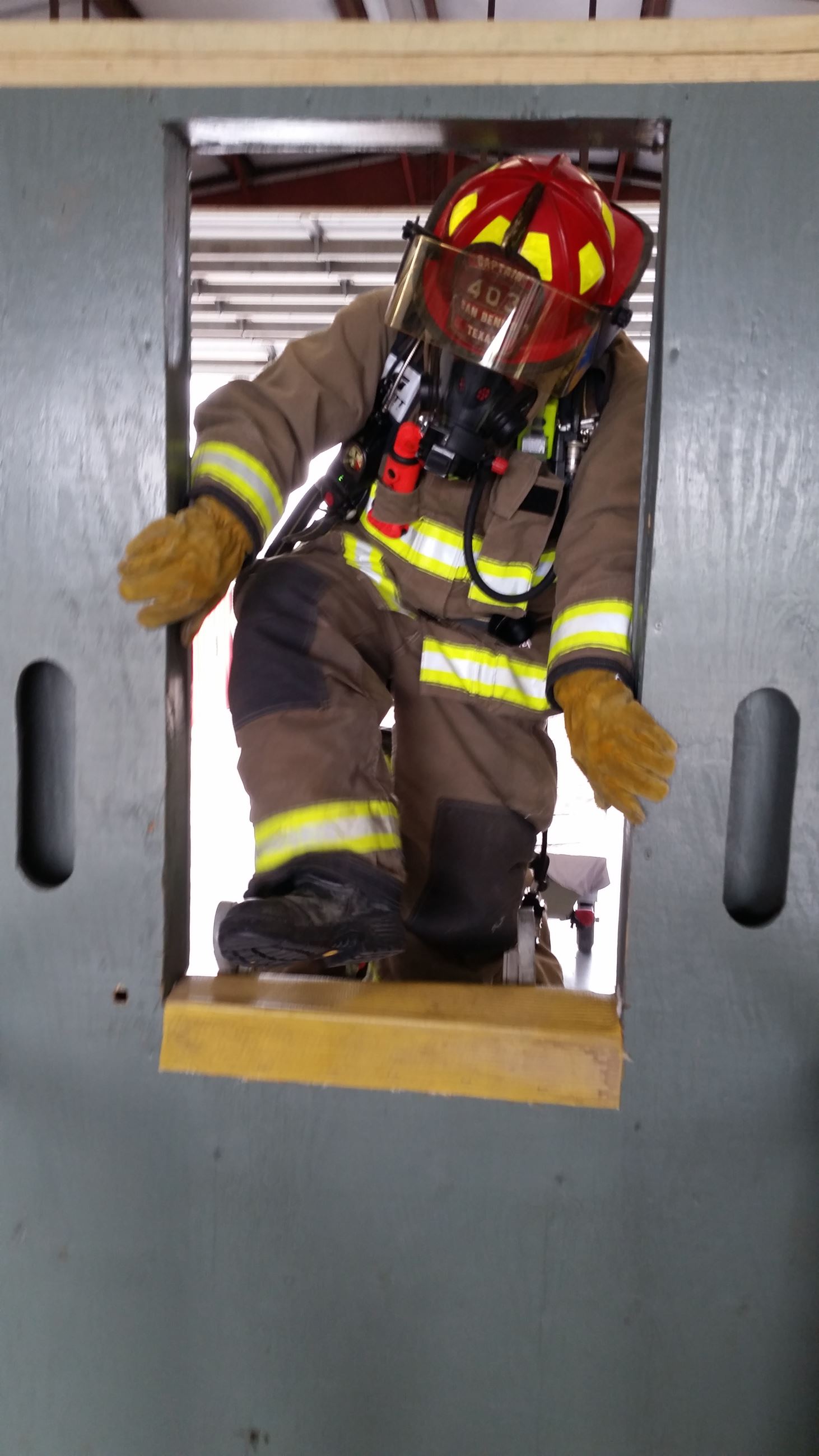 A firefighter climbs through an entry